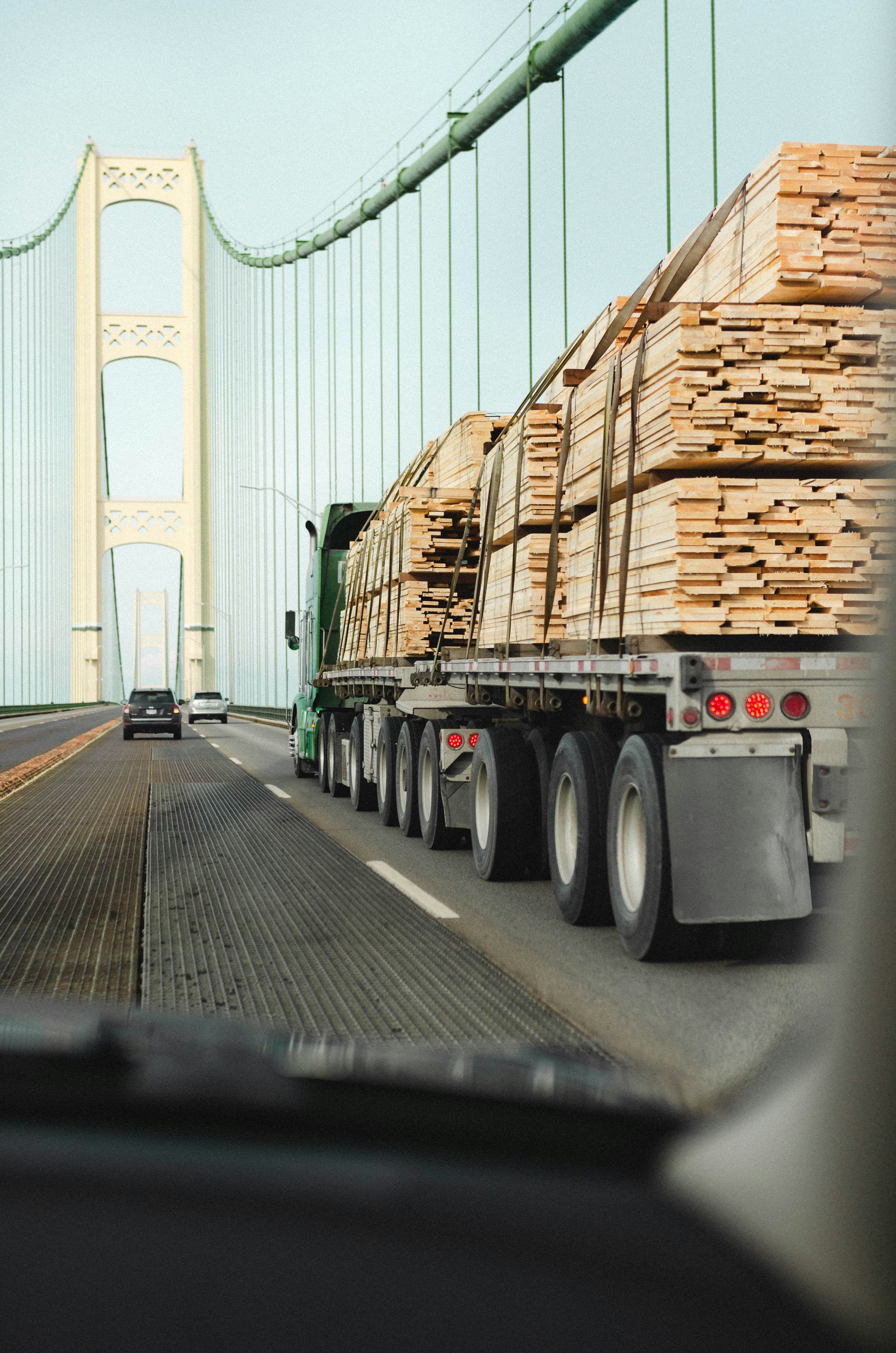 Flatbed truck hauling strapped bundles of lumber on a highway