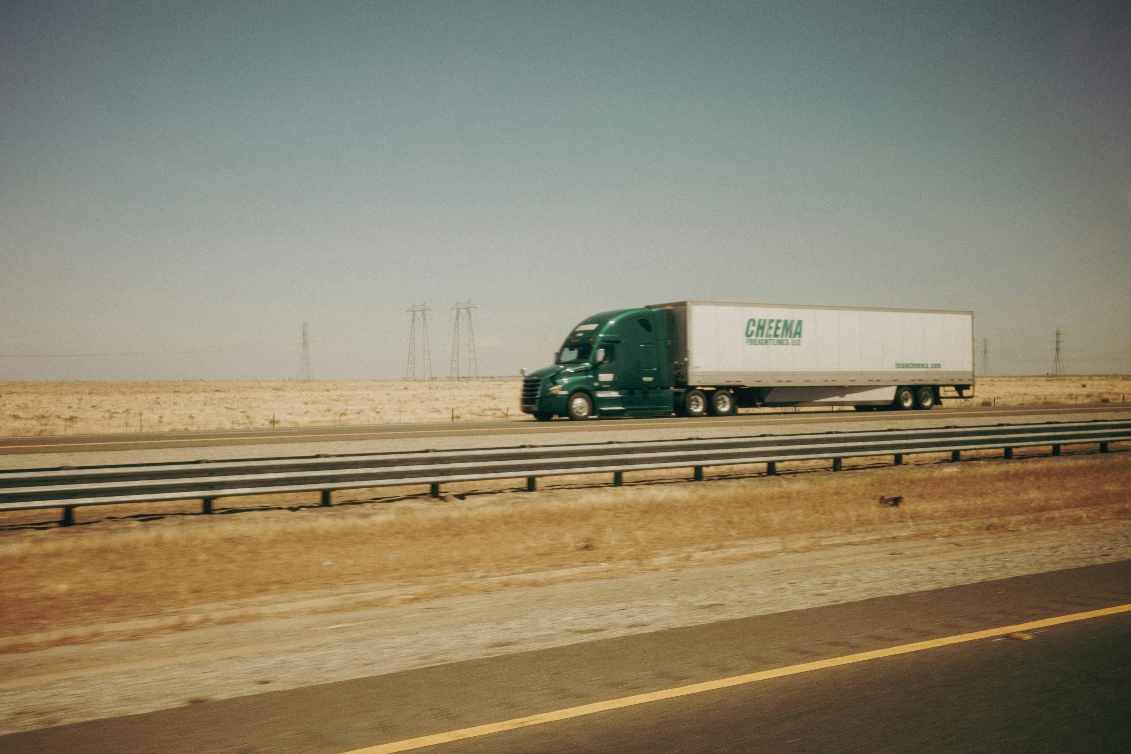 Semi-truck with an enclosed trailer on an open highway under a wide sky